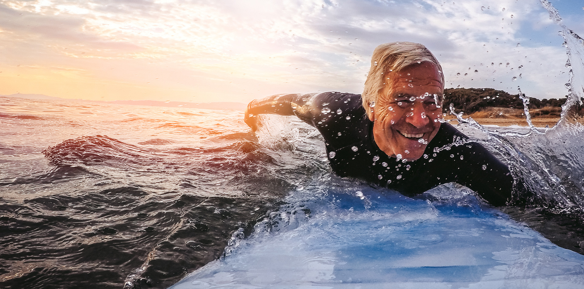 Sportlicher Herr in seinen 60ern der auf einem Surfbrett paddelt